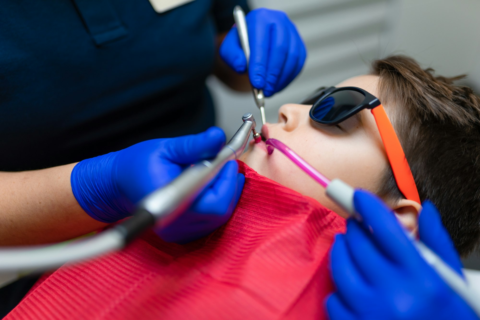 Dentist and assistant make preventive dental plaque cleaning for teenager